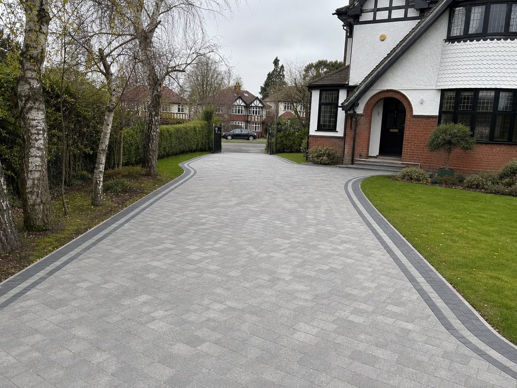 Long block paved driveway with twin charcoal border lines running to the gates in Dorridge