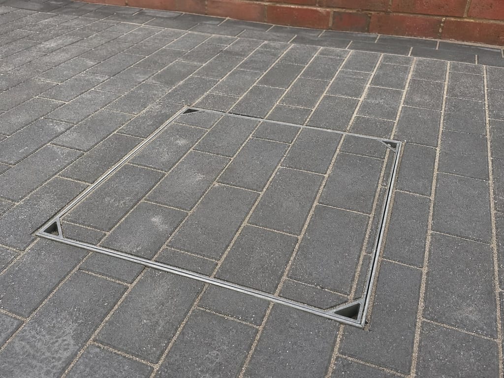 Recessed manhole cover tray set flush into new block paving